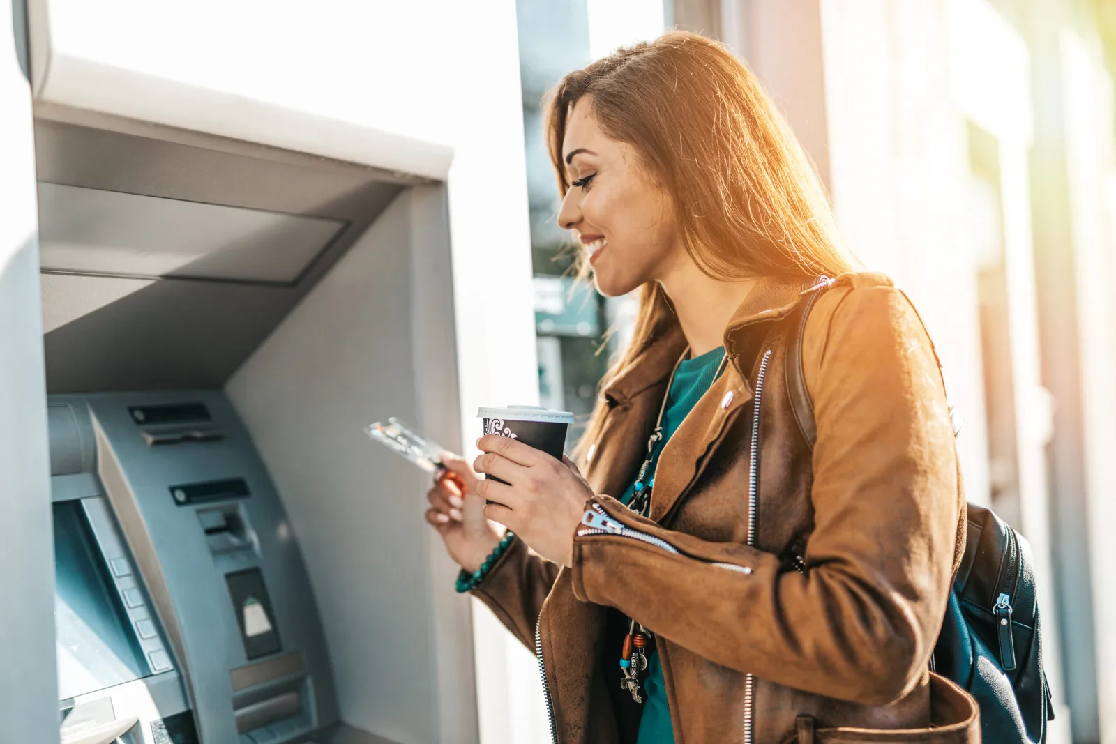 A customer withdrawing cash at an ATM in morning light